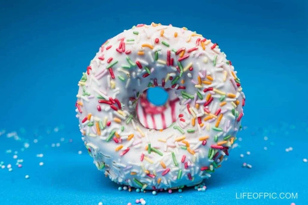 Close-Up Photo of a White Donut with Colourful Sprinkles